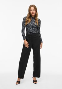 Long-sleeve top with a black and gray leopard print pattern, paired with high-waisted black wide-leg trousers and open-toe black heels.