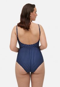 Bañador de una pieza en azul marino con puntos blancos, tirantes delgados ajustables y diseño de espalda baja. Tejido suave con ligero estiramiento.