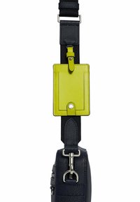 Cinghia in tessuto texturizzato blu navy con hardware in metallo, dotata di un portadocumenti ID in pelle verde brillante. La cinghia include sezioni regolabili e un gancio.