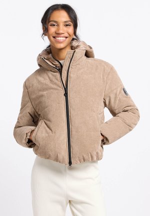 Beige corduroy pufferjack met een ritssluiting aan de voorkant, een oversized capuchon, geribde manchetten en zijzakken, gecombineerd met witte broek.