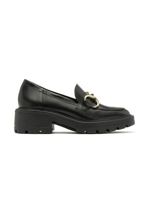 Mocasines de cuero negro con suela gruesa y de textura antideslizante, con un acento metálico en tono dorado en la parte superior. Textura suave y diseño clásico.