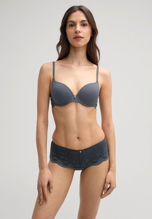 Grijze gepadde beha met dunne bandjes en kantafwerking; bijpassende kant boyshorts met golvende randen. Glad oppervlak en gouden accent op de tailleband.