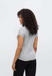 Γκρι πλεκτό τοπ με κοντό μανίκι, εφαρμοστό, με υφασμένες κάθετες ρίγες και στρογγυλή λαιμόκοψη, συνδυασμένο με μαύρο παντελόνι.