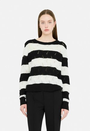 Maglione a righe bianche e nere realizzato in maglia, caratterizzato da un colletto rotondo, maniche lunghe e un motivo testurizzato con accenti diagonali.