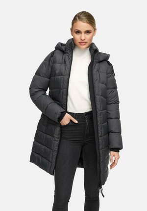 Black puffer coat with a hood, zip closure, and side pockets. Quilted design with a smooth texture, worn over a light-colored top and jeans.