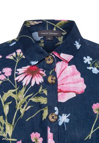 Bloemenoverhemd met een marineblauwe achtergrond, levendige roze en blauwe bloemen, twee bruine knopen en een kraag. Merkenlabel zichtbaar.
