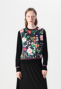 Black sweater with a floral-patterned front featuring pink, green, and red accents. Ribbed neckline and cuffs with striped details.