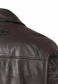 Donkerbruin leren jack met een gladde textuur, een klassieke kraag en een zichtbare naad over de rug. Accentuerend met een klein label nabij de kraag.