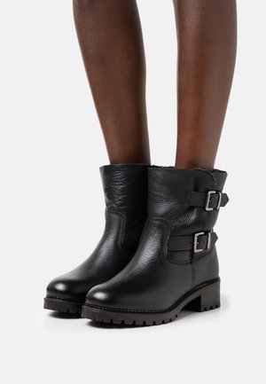 Schwarze Leder-Stiefeletten mit zwei silbernen Schnallen, strukturierter Oberfläche, rundem Zehenbereich und einer robusten profilierten Sohle. Oben mit einem komfortablen Futter versehen.