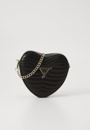 Sac noir en forme de cœur, en cuir matelassé, avec une bandoulière en chaîne dorée et un détail logo triangulaire sur le devant. Texture lisse.