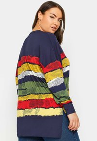 Pitkähihaisen paidan, jossa on vaakasuorat raidat punaisessa, vihreässä, keltaisessa ja valkoisessa. Valmistettu pehmeästä kankaasta, jossa on rento malli ja sivuhalkiot.