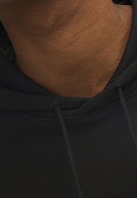 Felpa nera con cappuccio e cordini, realizzata in tessuto morbido, caratterizzata da una trama liscia e dettagli cuciti attorno al cappuccio.