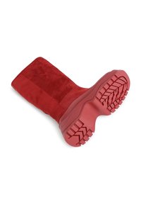 Stivale al ginocchio in suede rosso con una superficie texture e una suola in gomma spessa che presenta un motivo a battistrada accentuato per una migliore aderenza e durata.