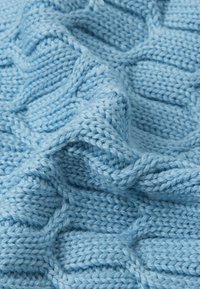 Tessuto a maglia blu chiaro con un motivo di trama a coste. Il filato appare morbido e leggermente peloso, mostrando i dettagli dei punti ritorti in tutto il tessuto.