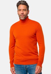 Helliges oranges Rollkragenpullover aus weichem Material. Passgenaues Design mit langen Ärmeln und gerippten Bündchen, kombiniert mit Jeans.
