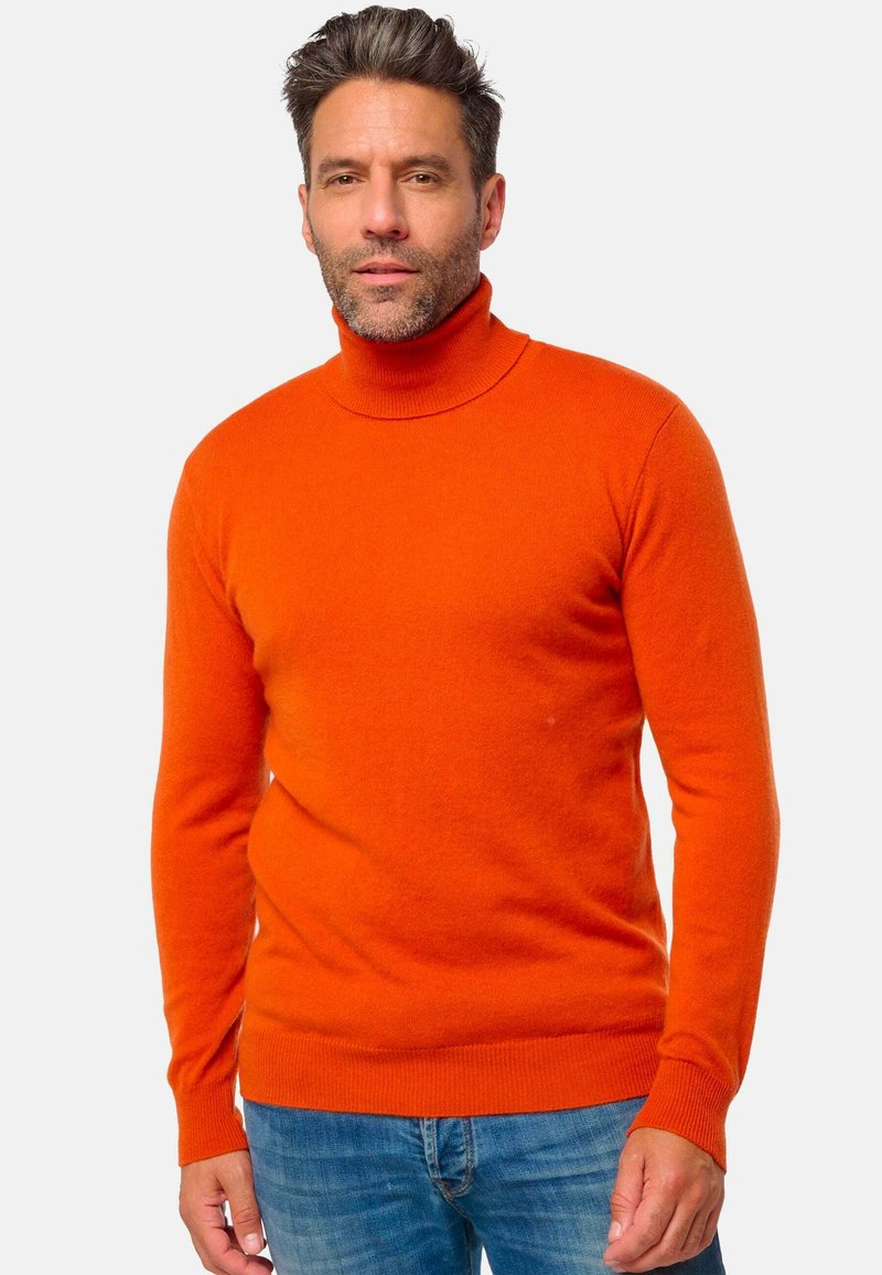 Helliges oranges Rollkragenpullover aus weichem Material. Passgenaues Design mit langen Ärmeln und gerippten Bündchen, kombiniert mit Jeans.