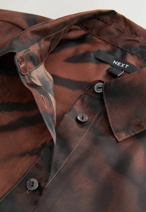 Barna és fekete mintás ing, gombos záródással, gallérral és "NEXT" feliratú címkével. Sima textúra és könnyű kialakítás.