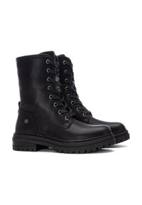Botas de tobillo de cuero negro con cordones, con suela de goma resistente, que cuentan con ojales de metal y un forro suave para mayor comodidad.