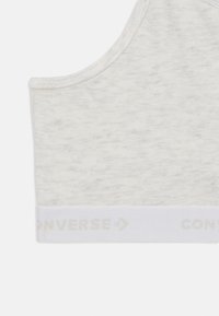 Vitt stretch sportbh med en melerad textur, med en bred elastisk rem med "CONVERSE"-logotyp i ljusgrått på botten.