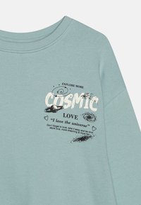 Sudadera de algodón azul claro con cuello acanalado, que presenta texto gráfico en negro e ilustraciones de un planeta y estrellas.
