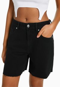 Mustat farkkushortsit, joissa on repaleinen helma, viisi taskua ja napitus. Mallissa on kapea istuvuus ja hieman joustavaa materiaalia mukavuutta varten.