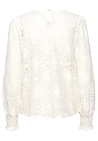 Blouse en dentelle blanche avec un motif floral, manches longues bouffantes, poignets smockés et une petite ouverture en forme de clé à l'arrière. Tissu texturé.