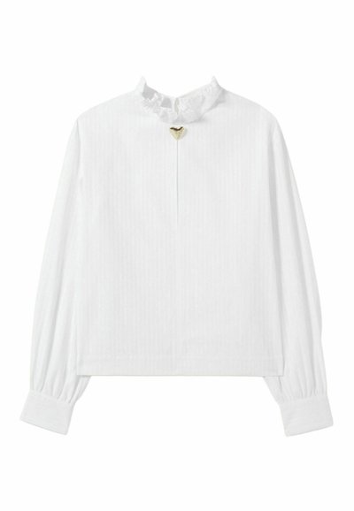 Blusa blanca de manga larga con un cuello con volantes y un pequeño detalle en forma de corazón dorado en el centro, con rayas verticales en toda la prenda.