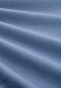 Tessuto azzurro chiaro con una texture liscia, che presenta fini motivi di tessitura e sottili ondulazioni sulla sua superficie.