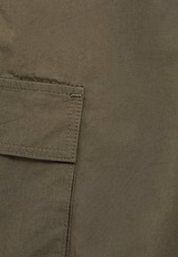 Échantillon de tissu vert olive avec une poche cousue, une texture lisse et un léger éclat. Design simple avec des éléments fonctionnels.