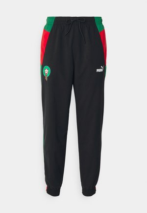 Pantalones jogger negros fabricados en un tejido suave, con paneles laterales en verde y rojo. Incluyen un parche con el logo y puños elásticos. Cintura con cordón.