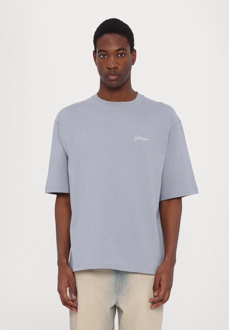 Grey short-sleeve t-shirt made of cotton, featuring a round neck and a small white logo on the chest. Soft texture and relaxed fit.