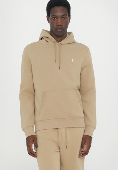Beige hoodie made of soft fabric, featuring a kangaroo pocket, drawstring hood, and embroidered logo on the chest.