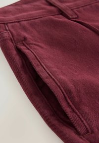 Bordeaux bomuldsbukser med en struktureret finish, der har sidelommer og syede detaljer. Stoffet har et blødt, let børstet udseende.