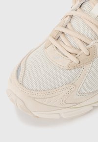 Krémová sportovní obuv má strukturovaný síťovinový svršek se semišovými akcenty, šněrování a polstrovaný límec pro pohodlí. Gumová podrážka pro lepší přilnavost.