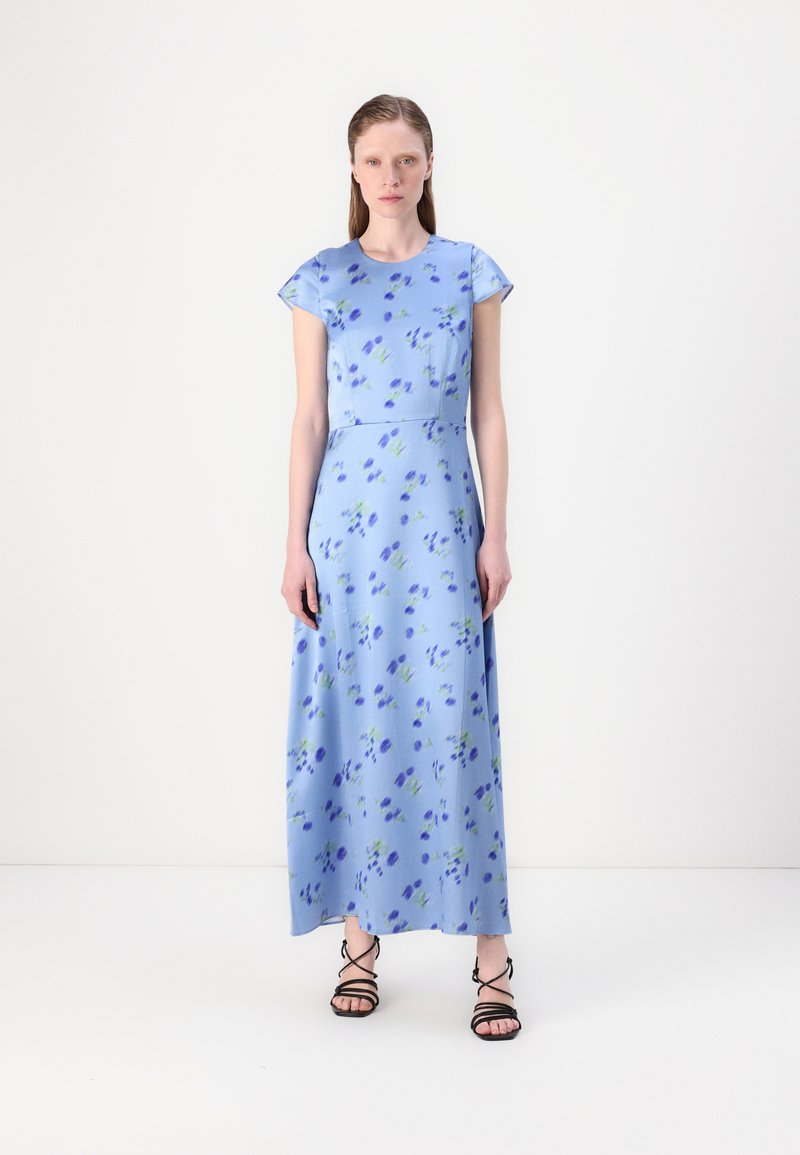 Maxi dress in light blue fabric with a floral pattern in dark blue and green. Short sleeves and a fitted bodice leading to a flowing skirt.