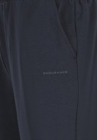 Marineblauwe joggingsbroek van zachte stof, met een elastische tailleband, zijzakken en een subtiele "ENDURANCE"-logo aan de voorkant.