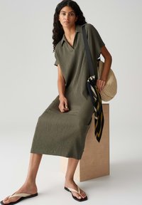 Olive green, short-sleeve dress with a collared neck, textured fabric, and a straight cut. Paired with a black strap bag and flip-flops.