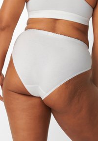 Perizoma hipster bianco in cotone con elastico a balze, caratterizzato da una texture liscia e cuciture minimali per comfort e vestibilità.