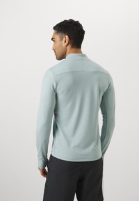Lyseblå langærmet skjorte med halv krave og sidepaneler i kontrast, glat tekstur, tætsiddende pasform og minimalistisk design.