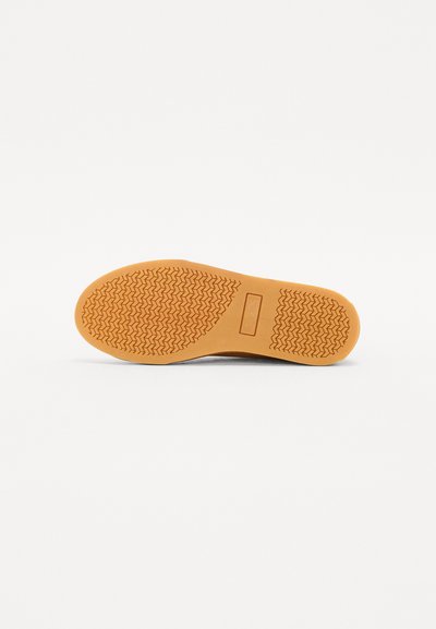 Talpa de pantof din cauciuc cu un model texturat, având o formă rotundă și o culoare solidă, caldă, de bej. Suprafață netedă cu o margine întărită.