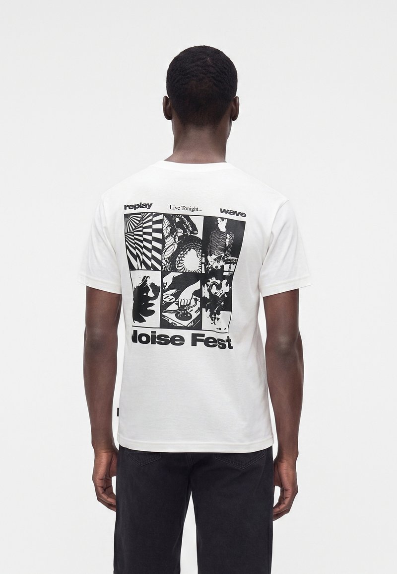 Άνδρας που φοράει λευκό T-shirt με μαύρα γραφικά πάνελ και κείμενο "Live Tonight... Noise Fest" στην πλάτη, στέκεται σε μονοχρωμο φόντο.