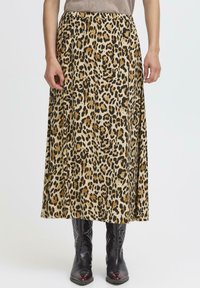 Zebra-print maksi suknja u bež i crnoj boji od materijala, s elastičnim pojasom za opušteni izgled. Uparena s crnim čizmama do koljena.