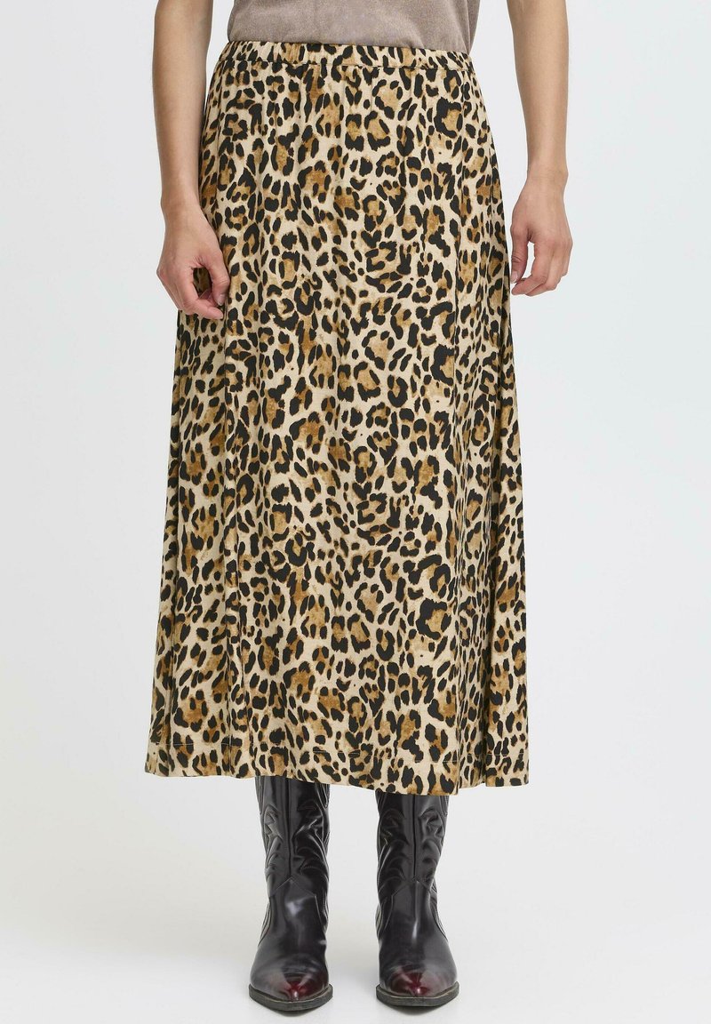 Zebra-print maksi suknja u bež i crnoj boji od materijala, s elastičnim pojasom za opušteni izgled. Uparena s crnim čizmama do koljena.