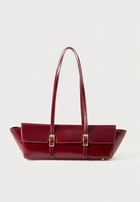 Burgundy leather handbag with two long, flat handles, two front pockets featuring gold buckles, and a tapered bottom design.