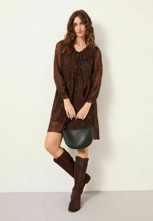 Langärmliges burgunderrotes Kleid mit floralem Muster und Rüschenausschnitt, kombiniert mit knielangen braunen Wildlederstiefeln und einer kleinen schwarzen Ledertasche.