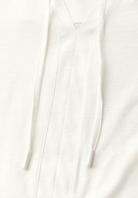 Witte hoodie met V-hals, voorzien van een gestructureerde stof, twee voorste trekkoorden met witte plastic punten en een subtiele gestikte patroon langs de halslijn.