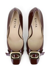Scarpe con tacco alto in pelle verniciata color bordeaux, con punta quadrata, grande fibbia dorata sul lato e morbida fodera interna beige.