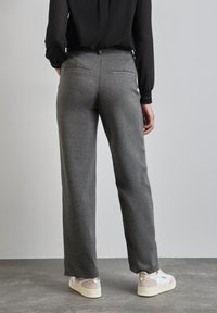 Wijde grijze broek gemaakt van zachte stof met een gladde textuur. Voorzien van achterzakken en te combineren met lichtgekleurde sneakers.