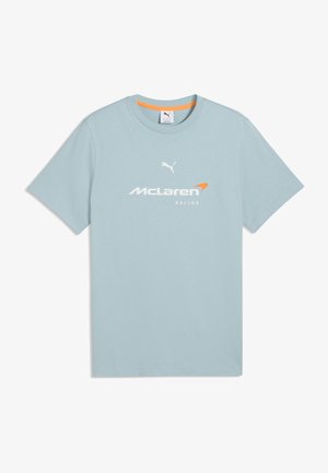 T-shirt bleu clair à manches courtes avec col rond, logos Puma et McLaren Racing blancs centrés sur la poitrine, avec un liseré orange à l'intérieur du col.