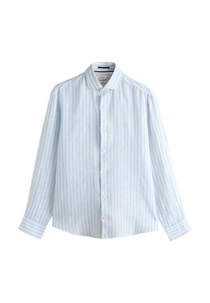 Közeli kép egy férfi arcának alsó részéről és nyakáról, aki világoskék-fehér csíkos gombos inget visel, amelynek a felső gombja ki van gombolva.